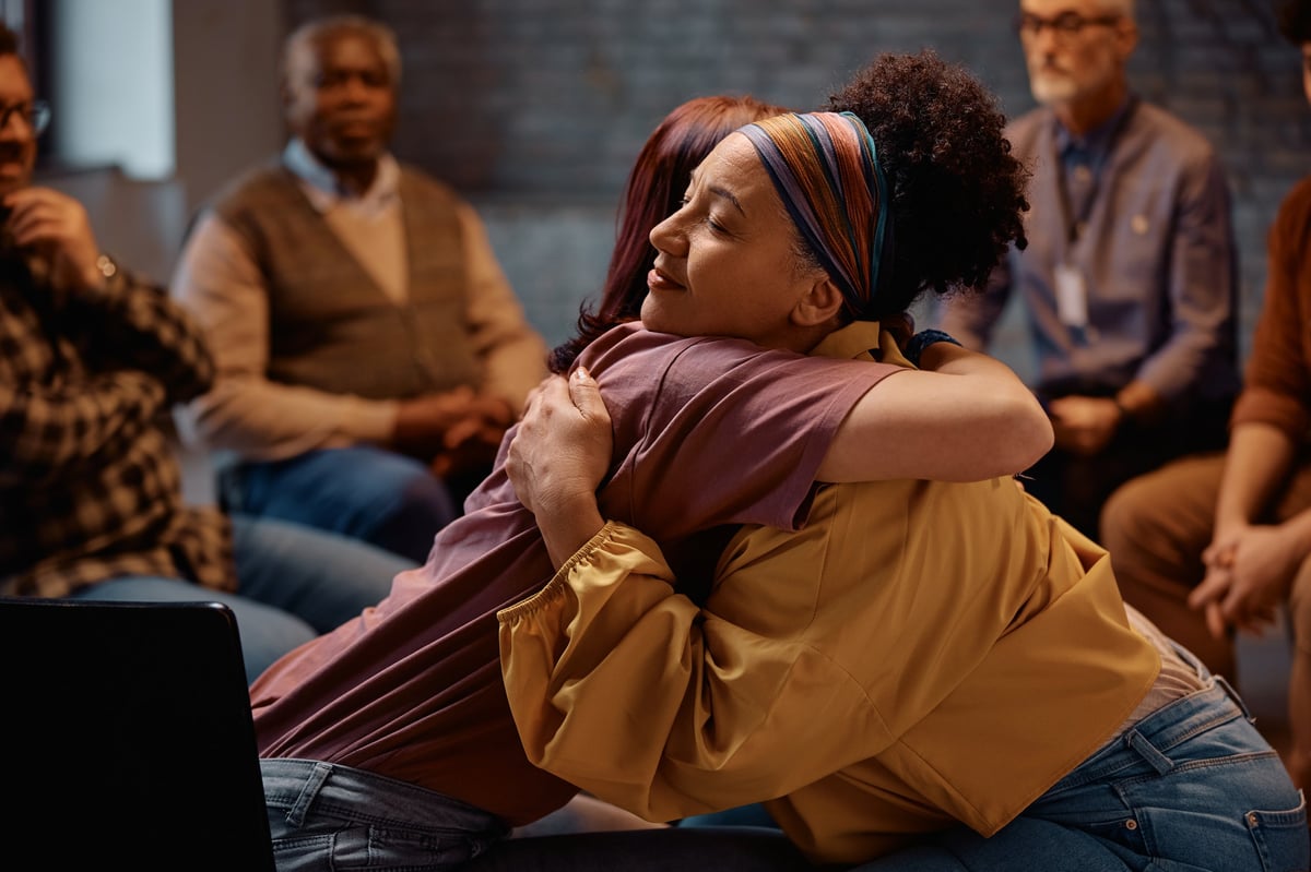 Group therapy participants embracing after a session