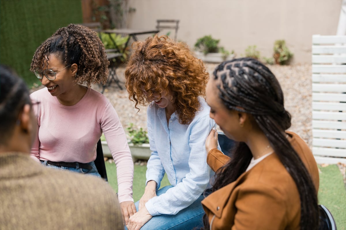 Diverse women laughing and sharing emotions during a supportive group session